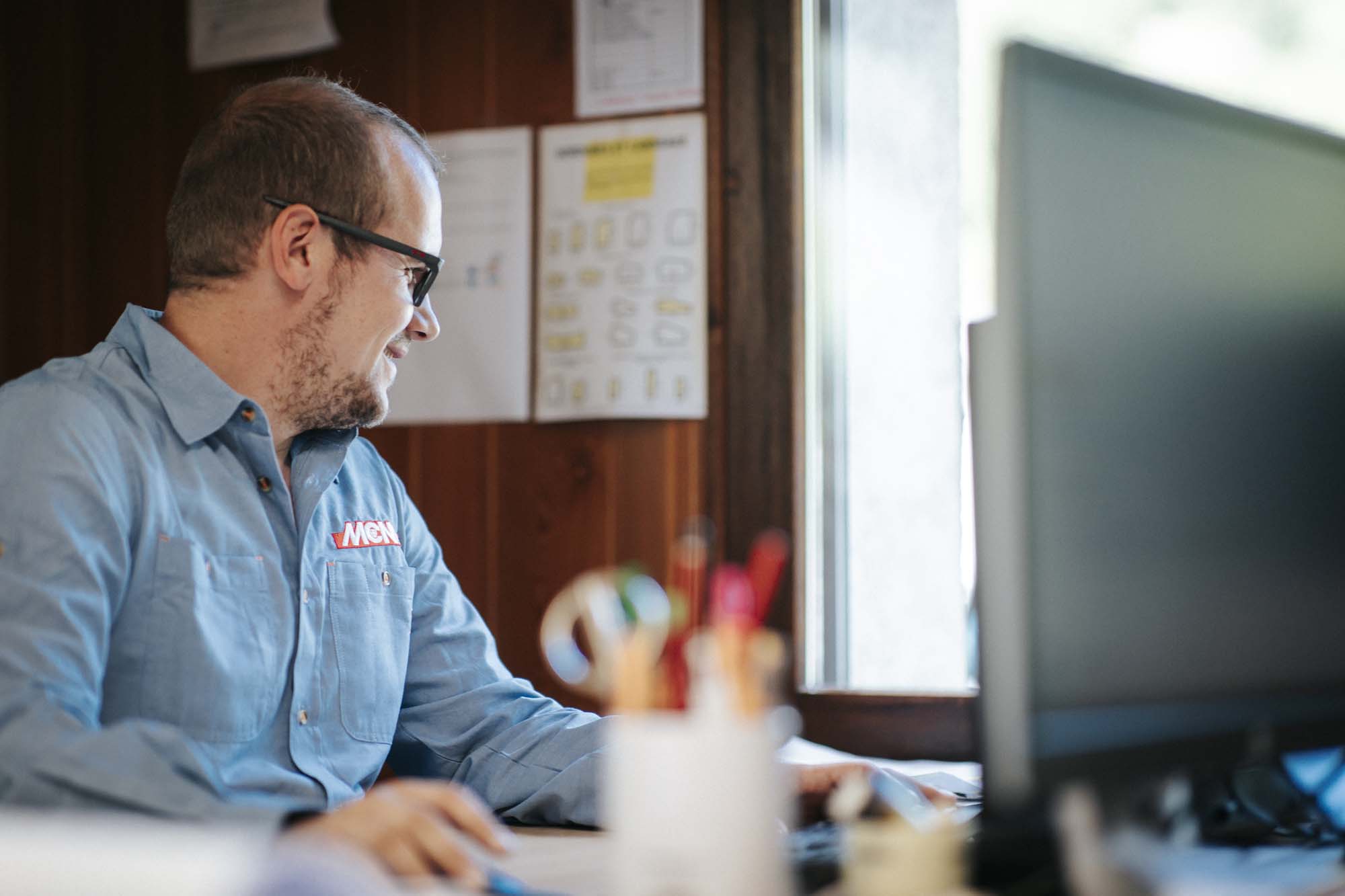Photo d'une personne assise sur un bureau devant un ordinateur - MCM TP