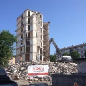 Bâtiment se faisant détruire par une pelle de démolition MCM