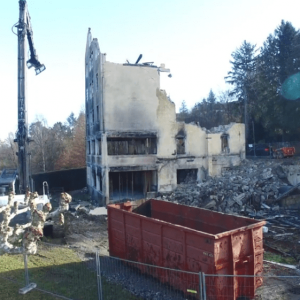 Bâtiment se faisant détruire par une pelle de démolition MCM